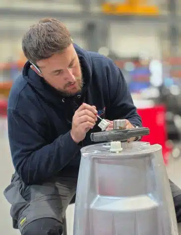 Engineer performing pump repair at Neutronic Technologies workshop, applying precision work on a pump component mounted on a metallic base.